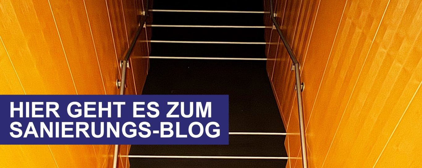 Treppen mit einem Geländer in einem Holzrahmen, der in die Dunkelheit führt.
